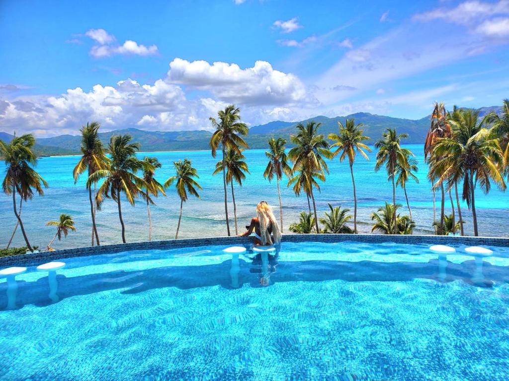 Eine Frau steht in einem Pool mit Meerblick in der Unterkunft Sunset Samana in Las Galeras