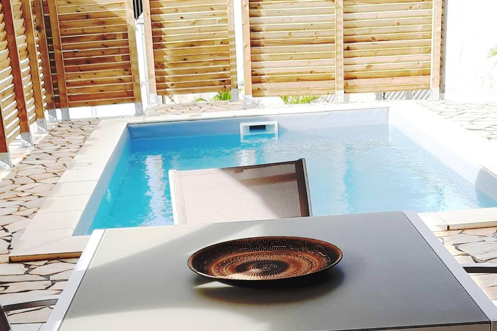 a bowl sitting on a table next to a pool at bungalow hibis.kiss971 in Baie-Mahault