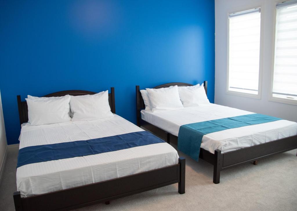 Duas camas num quarto com uma parede azul em PARADISE VILLa em Bowmanville