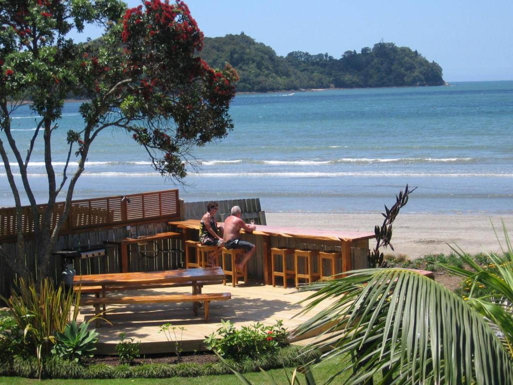 two people sitting at a bar on the beach at Beachfront Resort in Whitianga