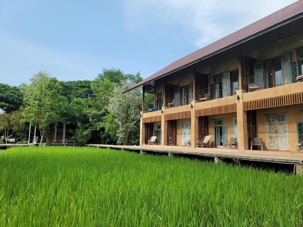 un gran edificio con un gran campo de césped verde en Phu-Anna Eco House, en Hot