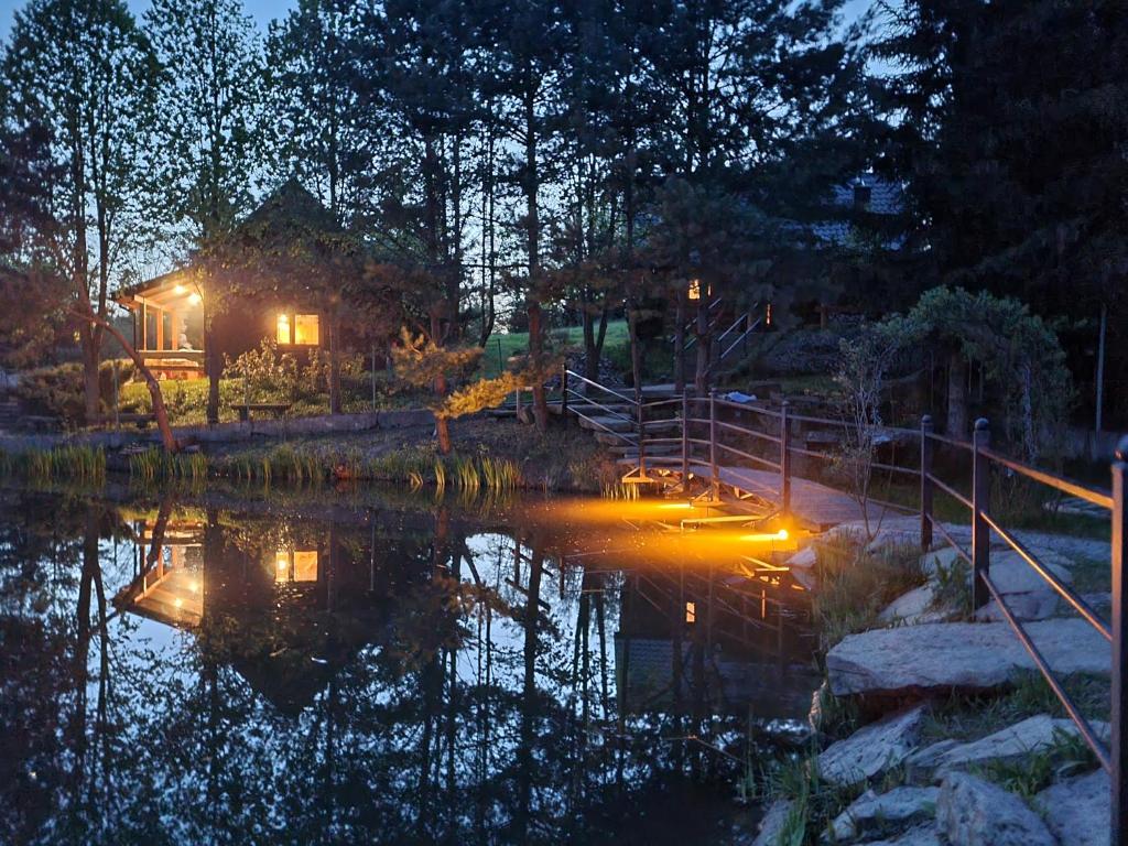 a house in the middle of a pond at night at Domek Nad Stawem I in Limanowa