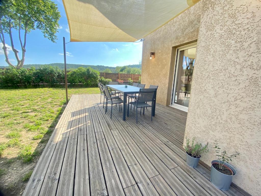 eine Holzterrasse mit einem Tisch und Stühlen darauf in der Unterkunft Villa neuve en Vaunage in Saint-Côme-et-Maruéjols