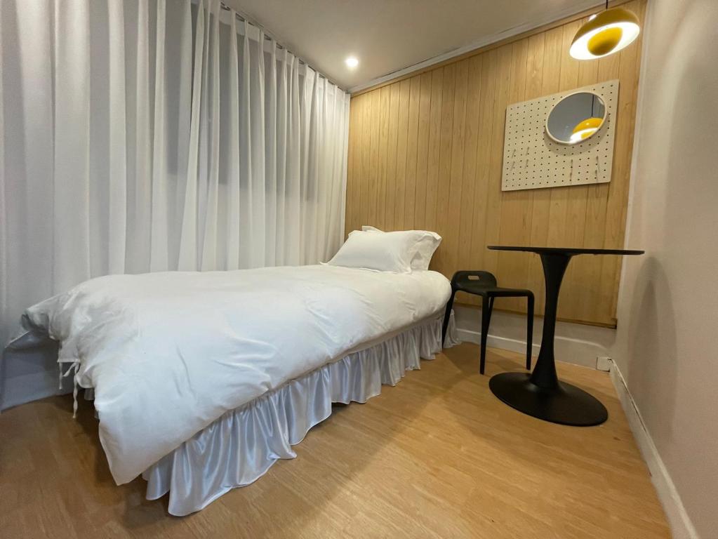 a bedroom with a white bed and a table at SSH LK Hostel in Seoul