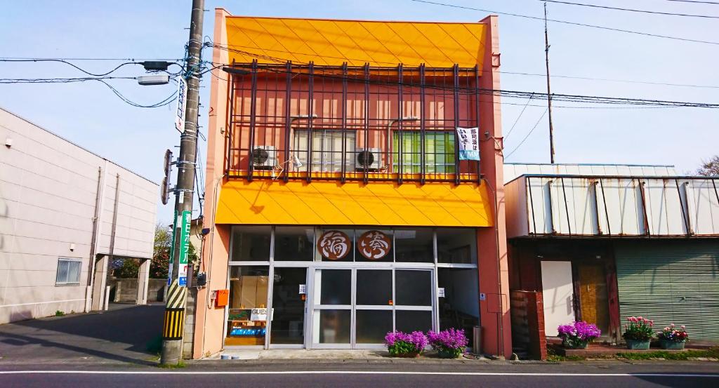a building with a yellow roof and a balcony at ゲストハウス 編湊 in Nakaminato