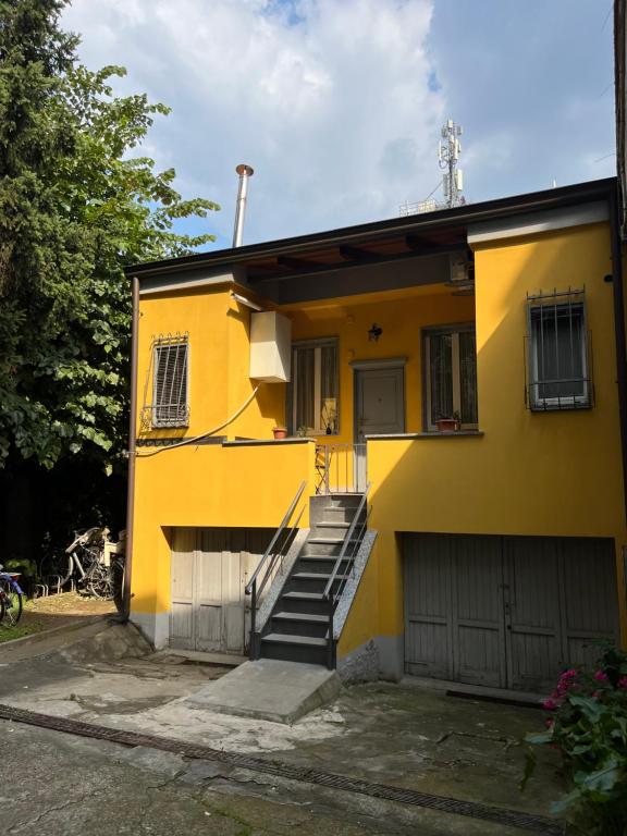 una casa gialla con scale e un garage di Gionas - Casa indipendente in zona strategica a Milano