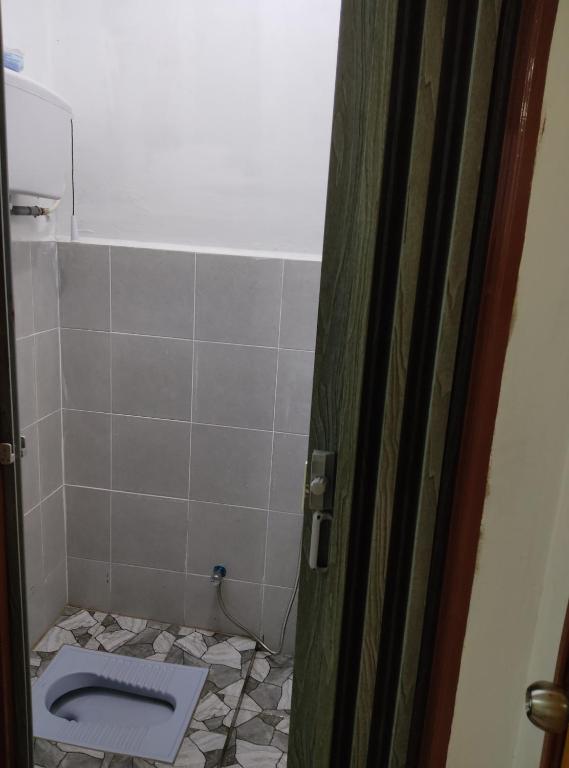 a bathroom with a toilet and a tiled floor at ARYAN HOMESTAY Temerloh in Temerloh