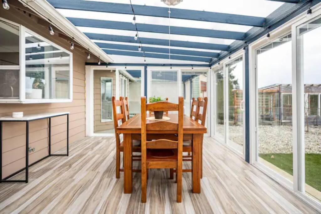 ein Esszimmer mit einem Tisch und einigen Fenstern in der Unterkunft Shiny Rambler House with Spacious Solarium. in Everett
