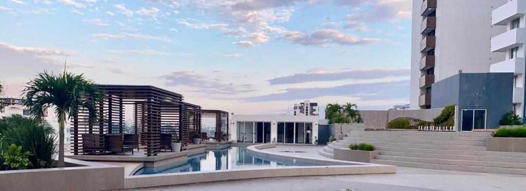 a building with a swimming pool in front of a building at Platinum II Equipetrol frente Ventura Mall Super Lujo Hermosas Vistas in Santa Cruz de la Sierra