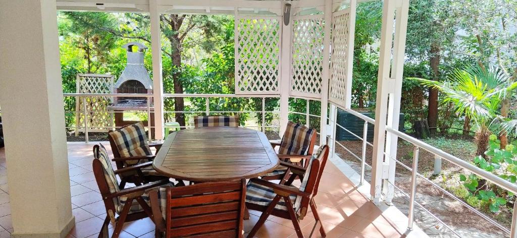 a screened porch with a wooden table and chairs at Vacation Home in Gjiri i Lalëzit, Lalëz, Durrës in Durrës
