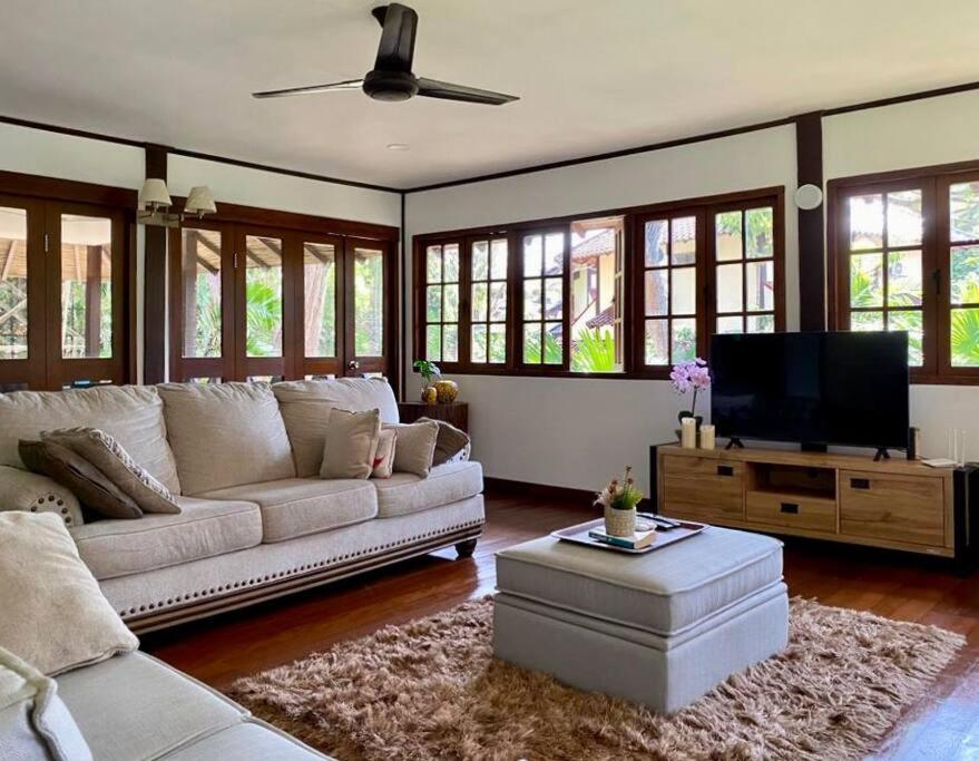 a living room with a couch and a flat screen tv at Private Tropical 3 Bedroom Villa - Nongsa Village Batam in Telukmataikan