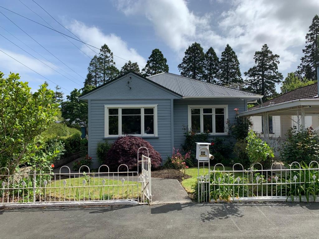 a blue house with a fence in front of it at Quiet home with modern touch in Dunedin