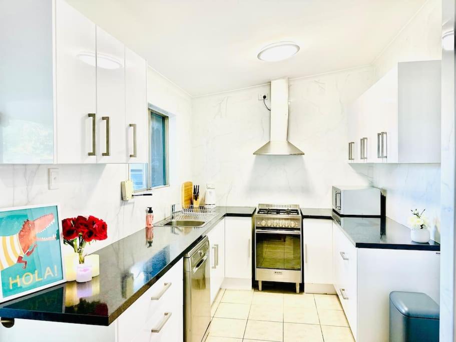 una cocina con armarios blancos y encimeras negras en Grabber- Three bedroom charm in Alice Springs en Alice Springs