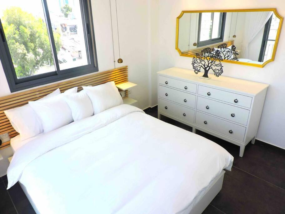 ein Schlafzimmer mit einem weißen Bett und einer Kommode mit einem Spiegel in der Unterkunft JLM market suite in Jerusalem