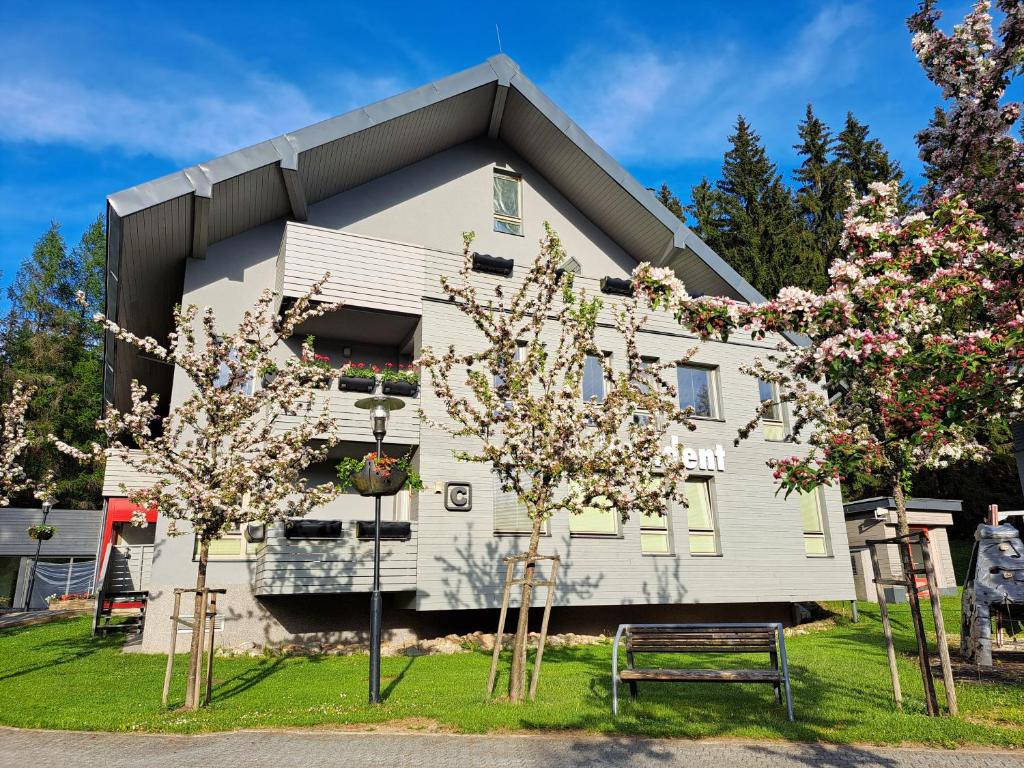 a white house with trees in front of it at Resident Harrachov Family apartment in Harrachov
