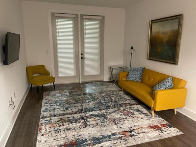 a living room with a yellow couch and a rug at Indulge in a luxury apartment in Lawrenceville