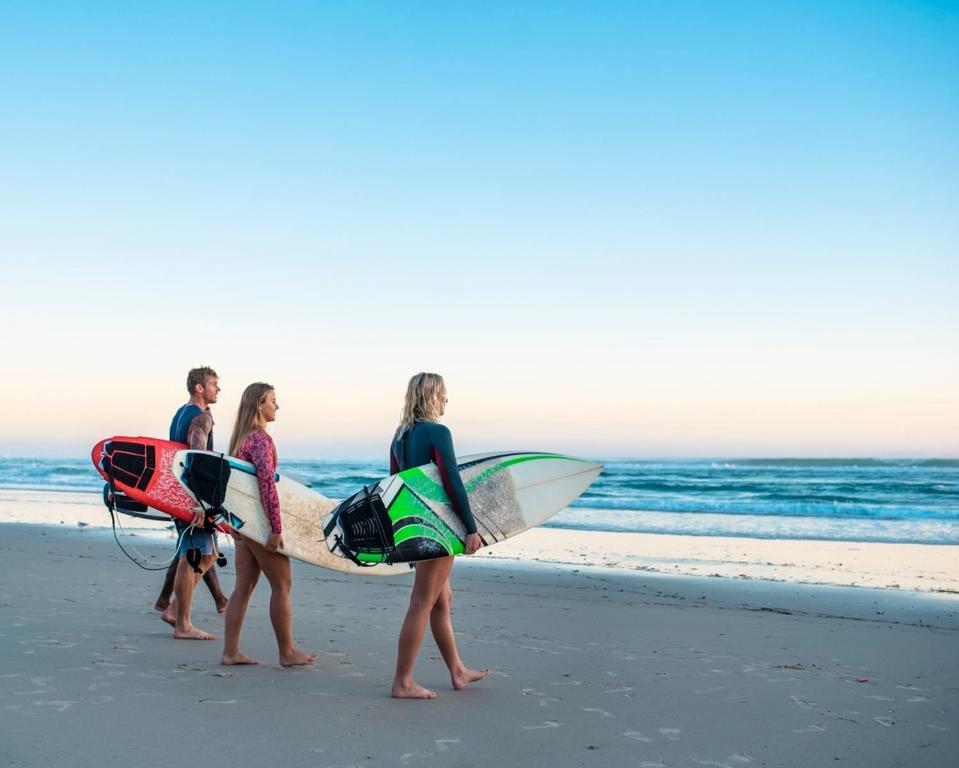 três pessoas andando na praia com suas pranchas de surf em Cosy villa with pool near ocean em Labenne