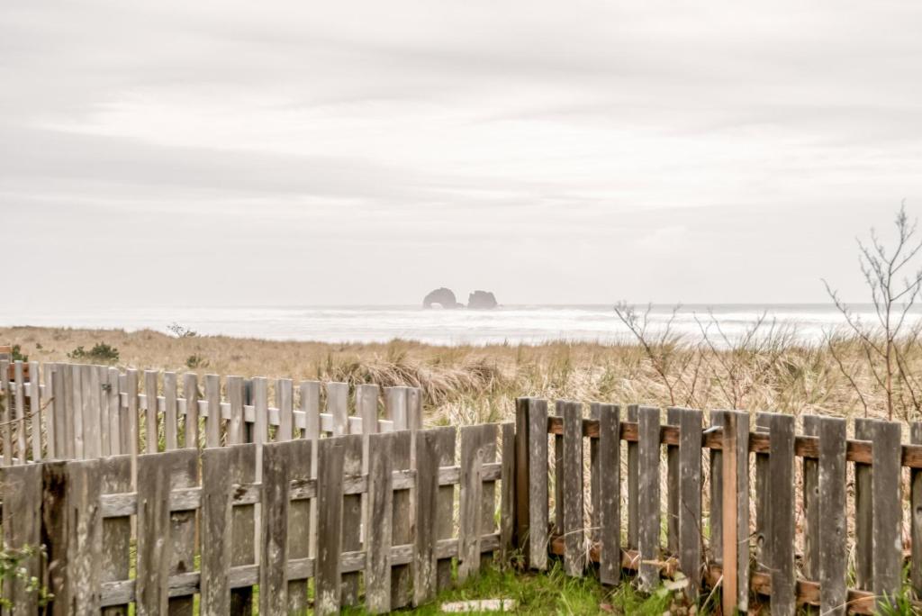 a fence at the beach with two rocks in the distance at The Hamptons in Rockaway Beach