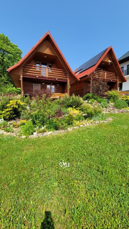 drewniany dom z zielonym trawnikiem przed nim w obiekcie domki nad jeziorem w Wołkowyi