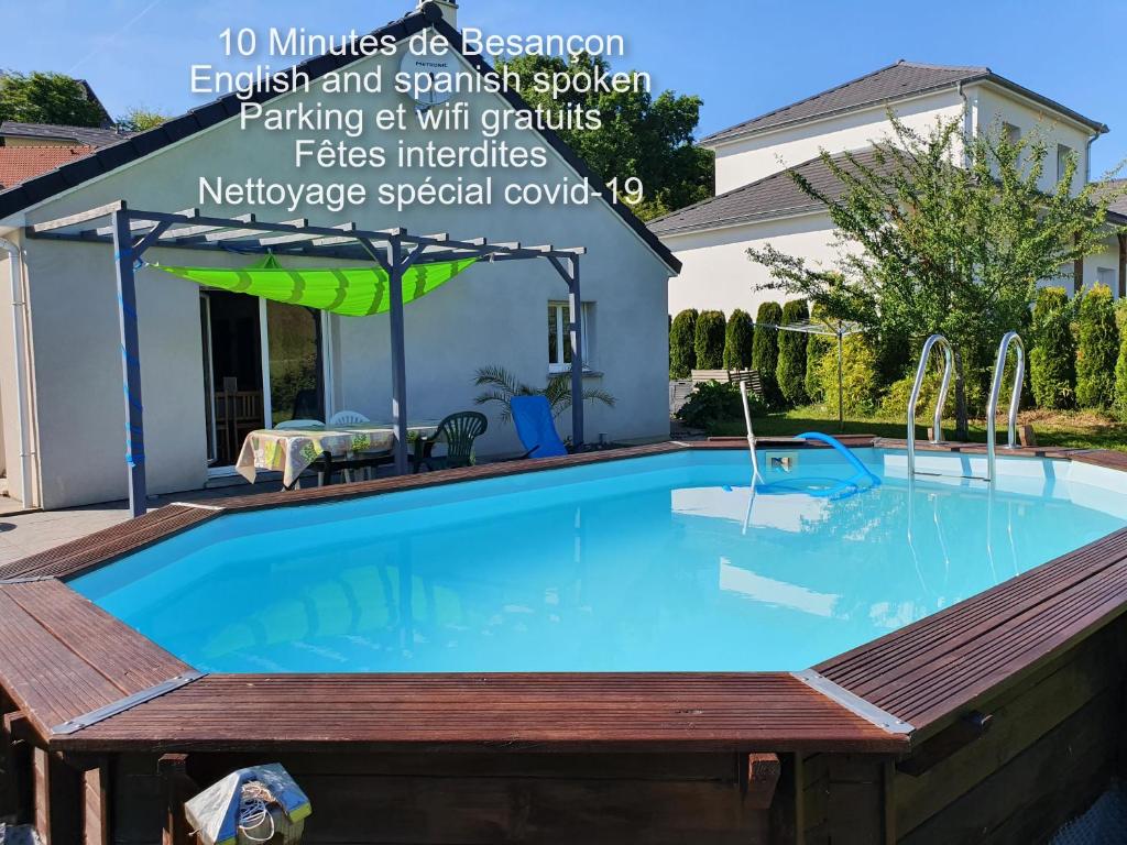 a swimming pool with a wooden deck around it at 1 chambre avec salle de bain privative ds maison plain-pied 105m2 à Montfaucon 10 minutes de Besancon in Montfaucon