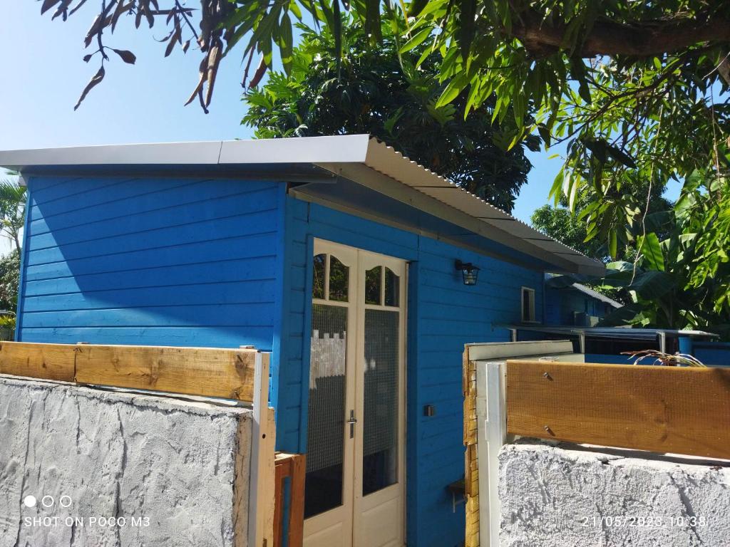 une petite maison bleue avec une porte blanche dans l'établissement Bungalow bleu, à L'Étang-Salé