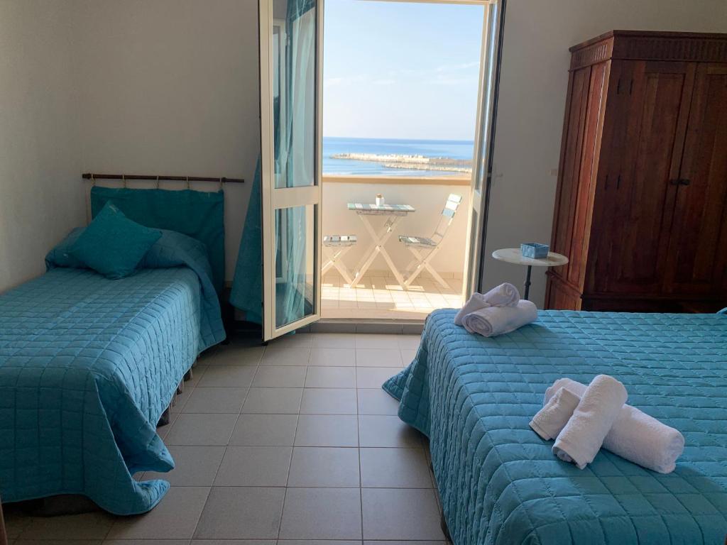 1 dormitorio con 2 camas y vistas al océano en La Bussola en Porto Palo