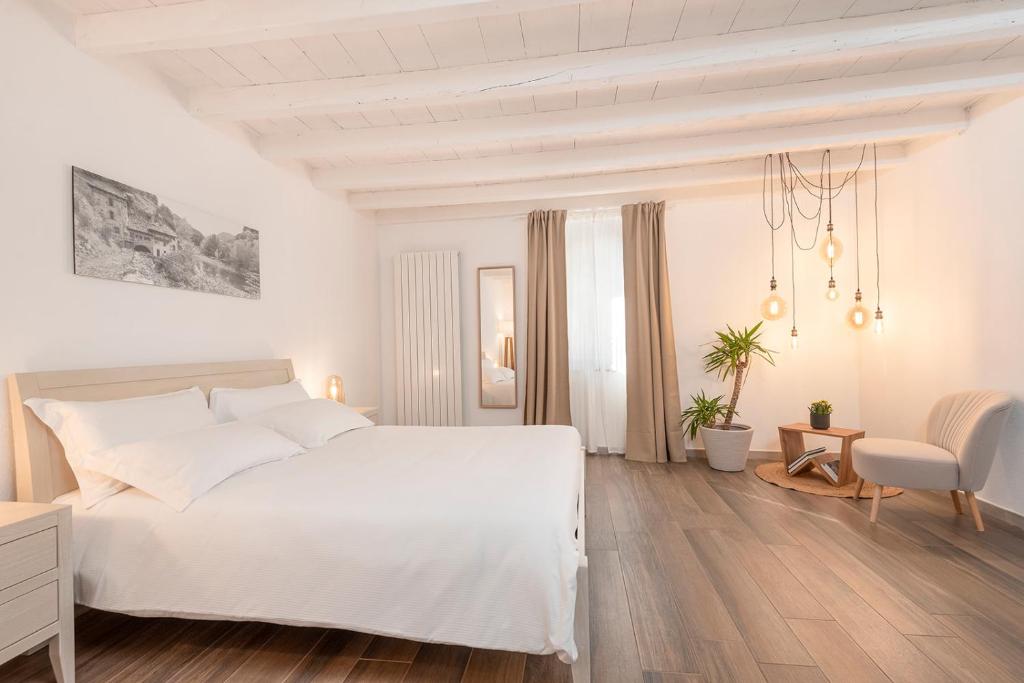 a white bedroom with a white bed and a chair at Porto di Clanezzo in Clanezzo