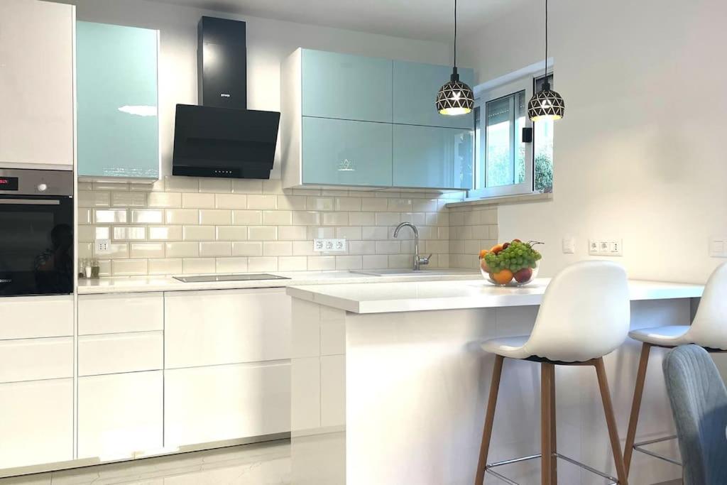 a white kitchen with white cabinets and white bar stools at At Jenny in Omiš