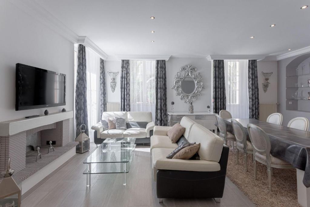 Il comprend un salon doté d'un mobilier blanc et une salle à manger. dans l'établissement Duplex Saint-henry by Halldis, à Cannes