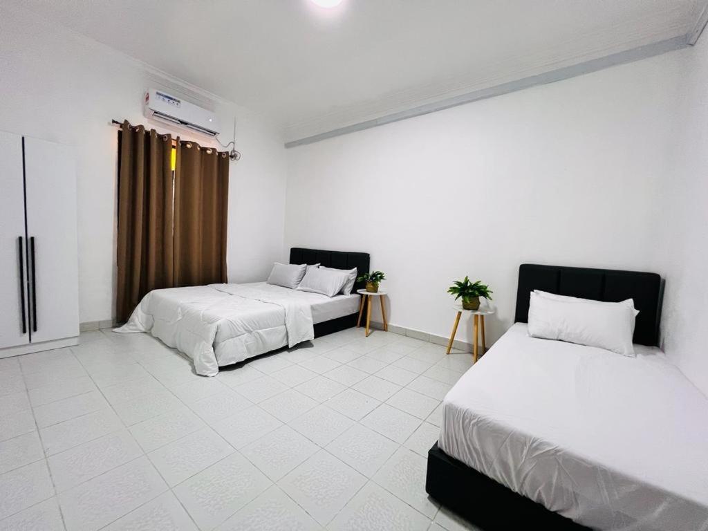 two beds in a room with white walls and white floors at HOMESTAY TOK ABAH in Kuala Berang