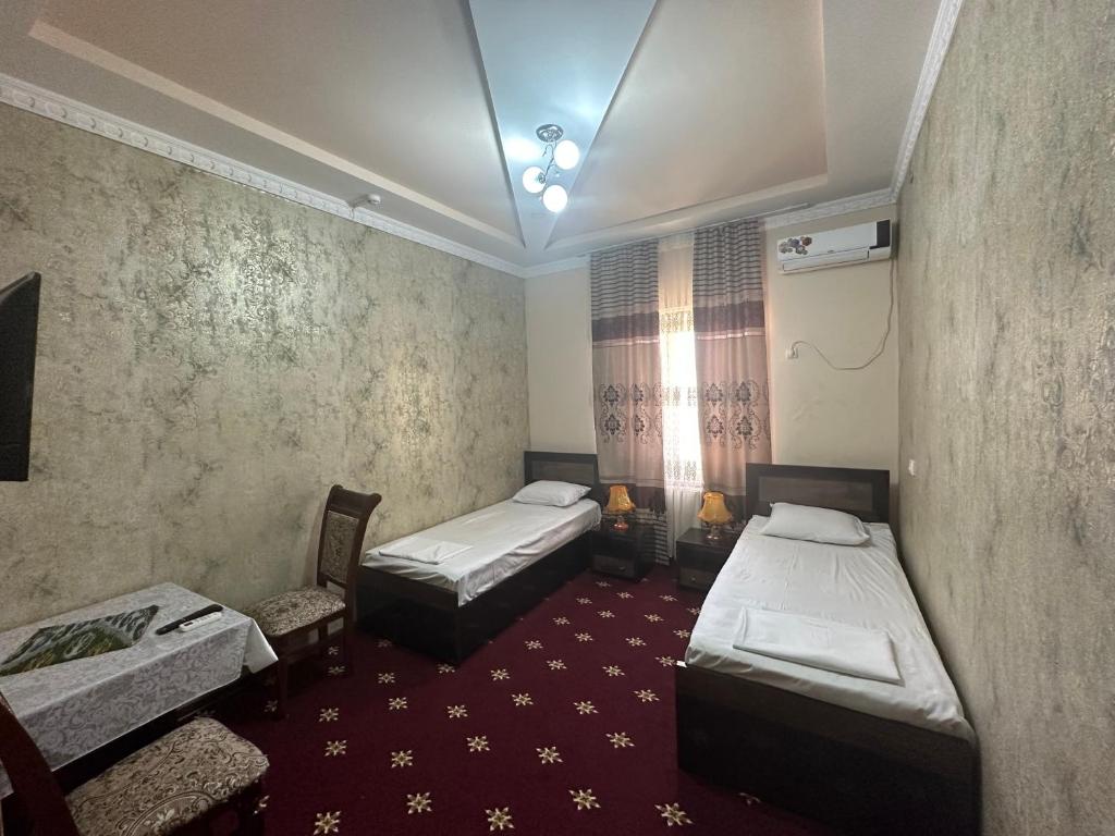 a room with two beds and a table and chairs at Mumtoz Plaza in Bukhara