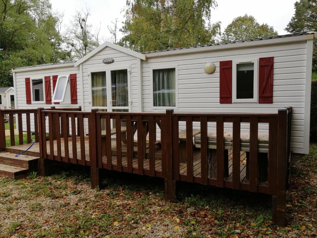 une petite maison blanche avec une terrasse en bois dans l'établissement Mobil-home ( dépaysement total à 40 km de paris ), à Saint-Chéron