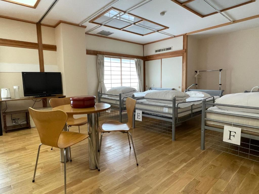 ein Krankenhauszimmer mit 3 Betten sowie einem Tisch und Stühlen in der Unterkunft Kawaguchiko Station Inn in Fujikawaguchiko