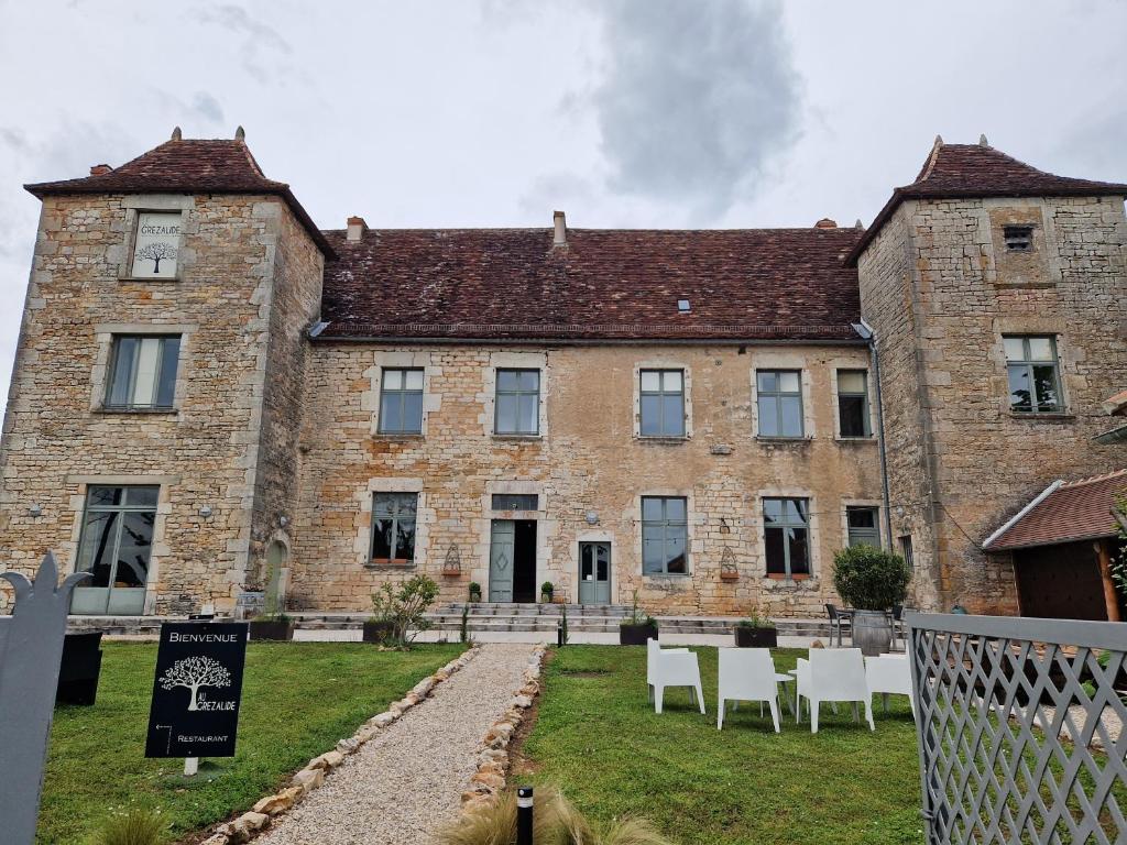 a large brick building with white chairs in front of it at Hotel Restaurant Le Grézalide in Grèzes