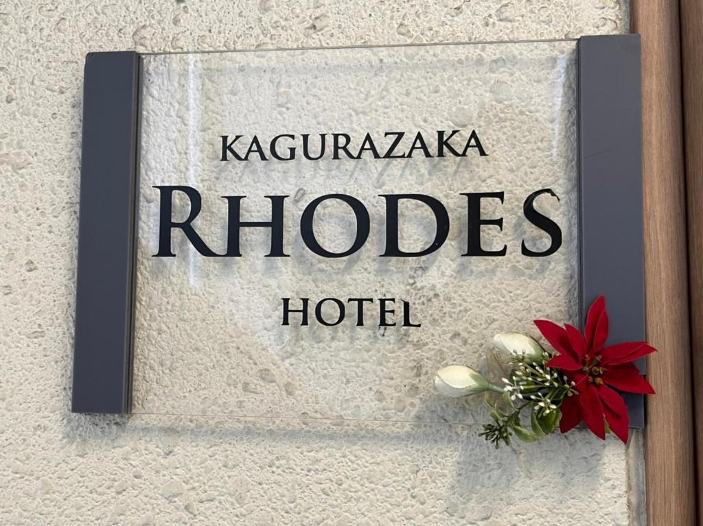a sign for a hotel with a red flower on a wall at Rhodes Kagurazaka in Tokyo