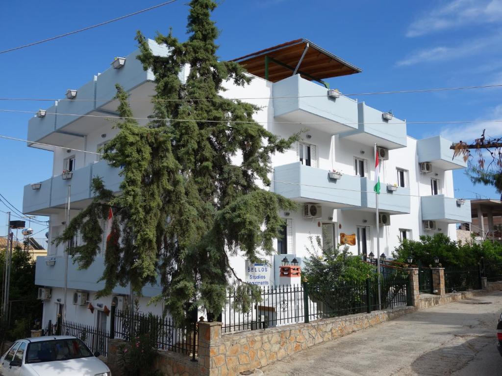 a white building with a tree in front of it at Studio Bellos in Tolo