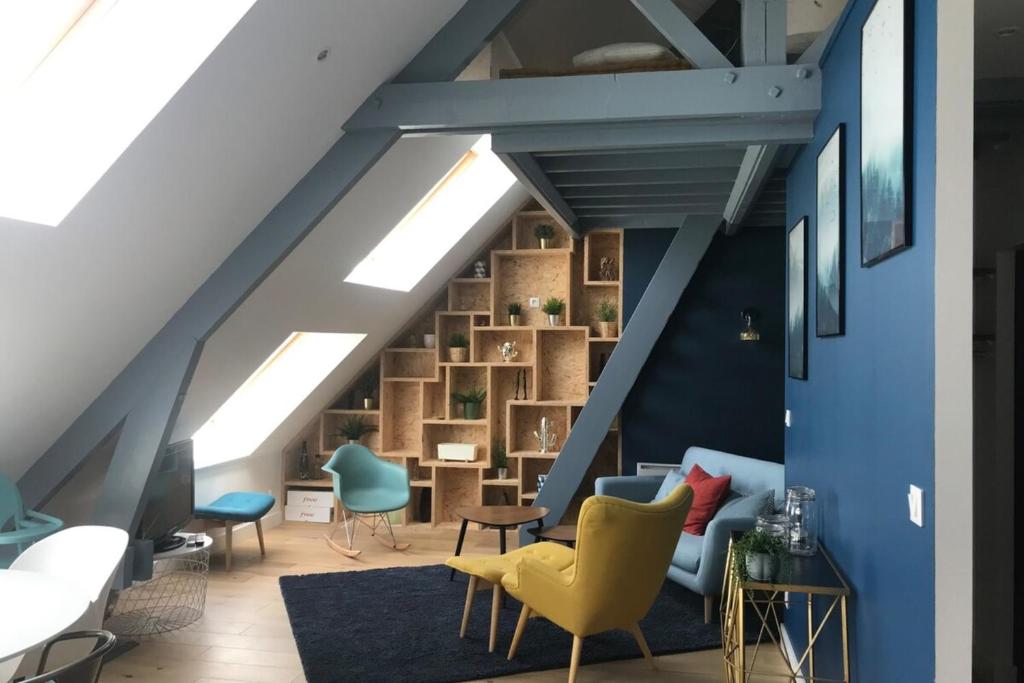 uma sala de estar no sótão com paredes azuis e cadeiras amarelas em Place 6 nice apartment in the heart of Arromanches em Arromanches-les-Bains