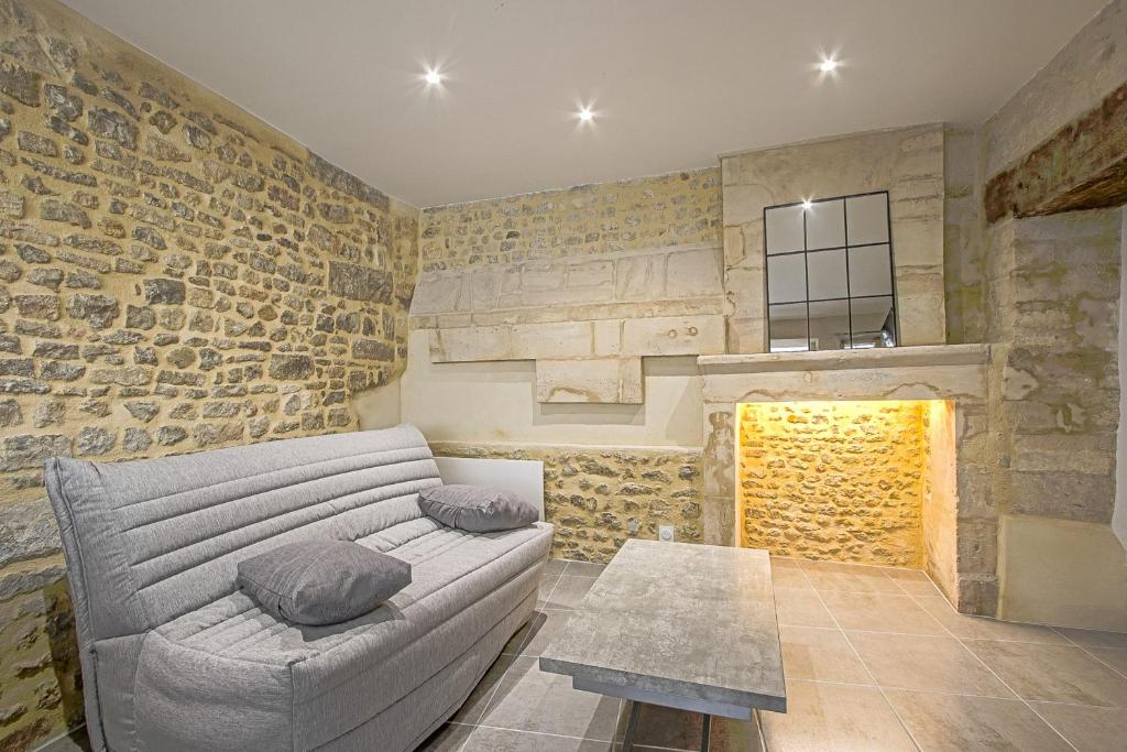 a living room with a couch and a stone wall at La cour des teinturiers in Bayeux
