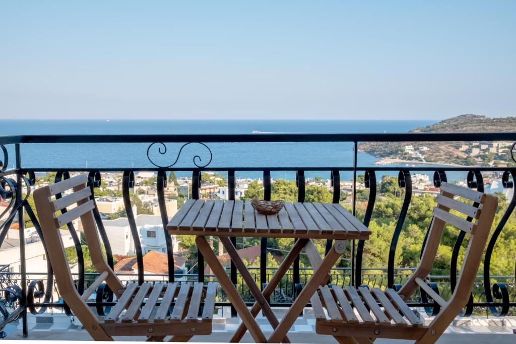 uma mesa de madeira e 2 cadeiras numa varanda em Pefkides Aegina Boutique Apartments em Agia Marina