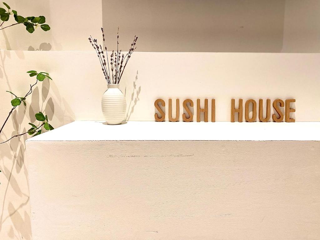 Un cartello per una sushi house con un vaso sul bancone. di Sushi Old Corner homestay No16 Lane38 Hang Bun St a Hanoi