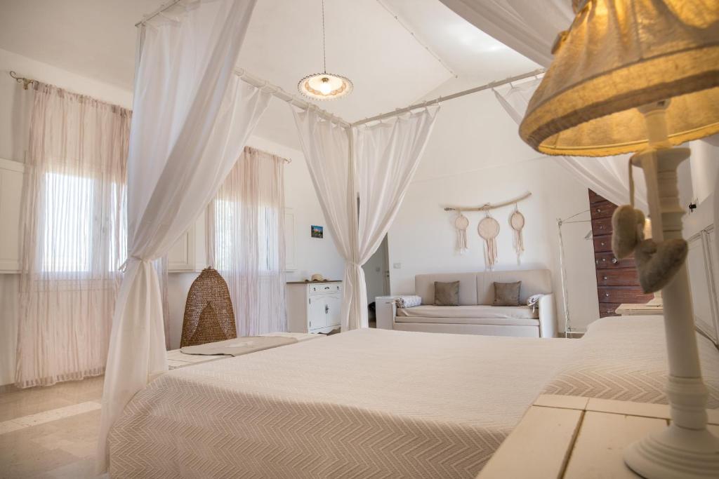 a white bedroom with two beds and a couch at Antica Masseria Ficazzana - Tenuta in Marina di Pescoluse