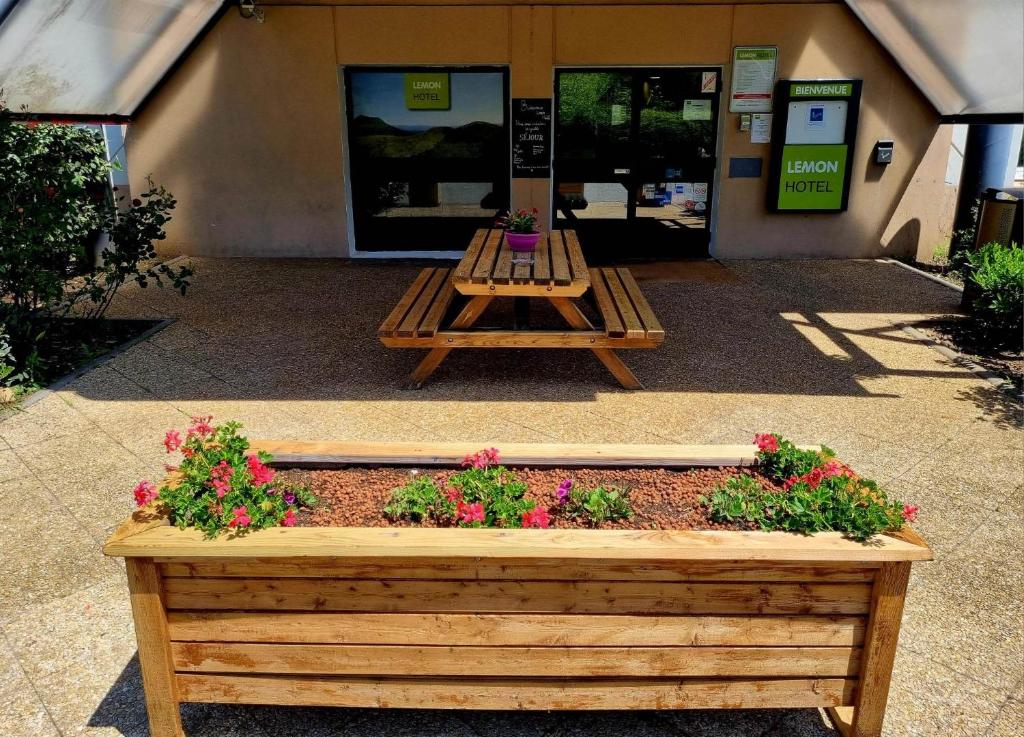 a wooden bench in front of a building with flowers at Lemon Hôtel Coudes in Coudes