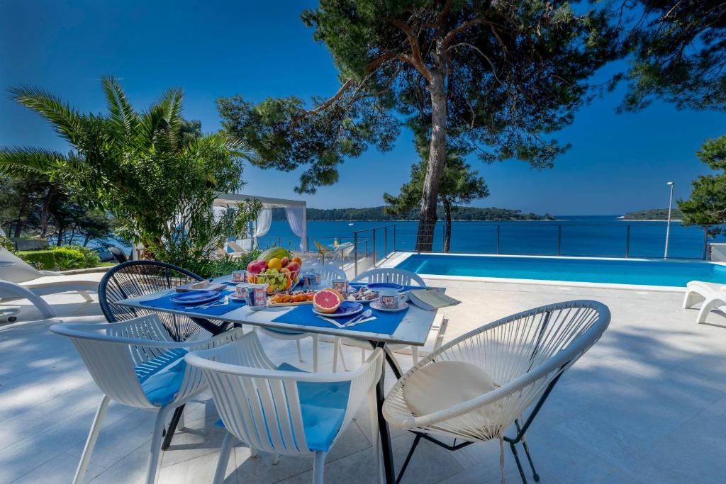 a table with a plate of food on it next to a pool at Villa Hana Croatia in Mali Lošinj