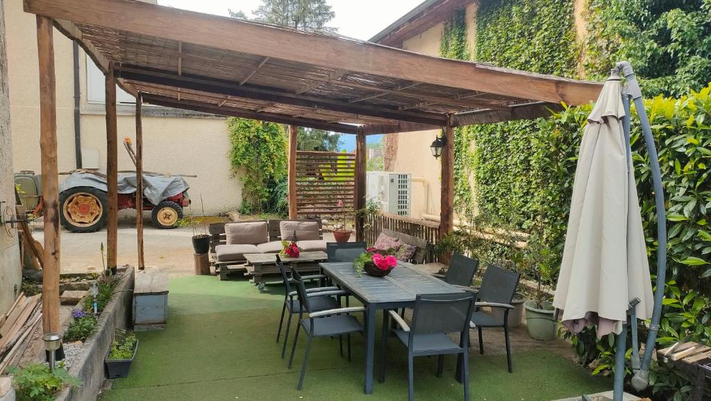 a patio with a table and chairs and an umbrella at Chez Rachel et Karim in Chindrieux