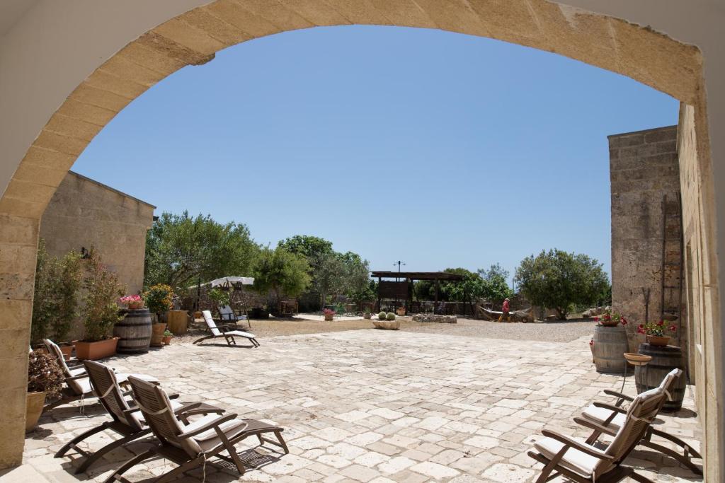 an archway with lounge chairs on a patio at Antica Masseria Ficazzana - Tenuta in Marina di Pescoluse