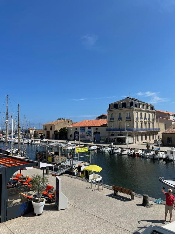 une femme prenant une photo d'un port de plaisance avec des bateaux dans l'établissement La maison du Port Apt ROMA, à Marseillan
