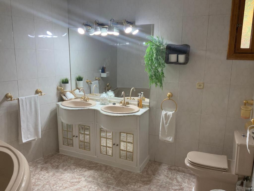 uma casa de banho com 2 lavatórios, um espelho e um WC em Casa Hermi em Arenas de San Pedro