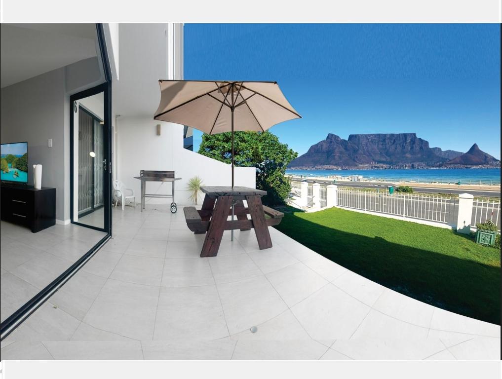a patio with a table and an umbrella at Cap du Mont in Bloubergstrand