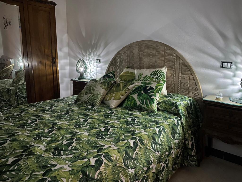 1 dormitorio con cama con colcha verde y almohadas en Le Foglie di Lubo, en Aulla