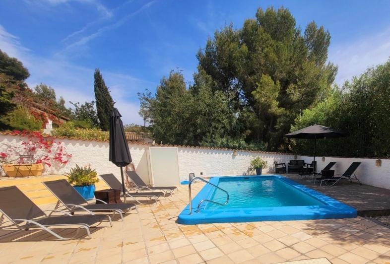 a swimming pool with chairs and an umbrella at Casa Blanca Suiza in Benissa